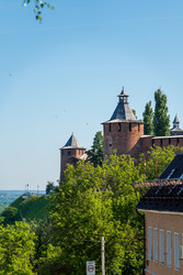 Нижний Новгород, Россия. Тайницкая и Северная башни Нижегородского Кремля, круглые кирпичные укрепления с деревянными черепичными крышами, возвышаются над зеленым склоном холма под ясным голубым небом - NikitaMaykov