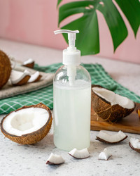Прозрачная бутылка мыла с половинками кокоса на светлом фоне. Генеративный ИИ - RomanZ