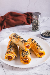 Жареные булочки с сосисками, сыром, питой и кунжутом на тарелке на столе (вид сверху) - Elena Rui