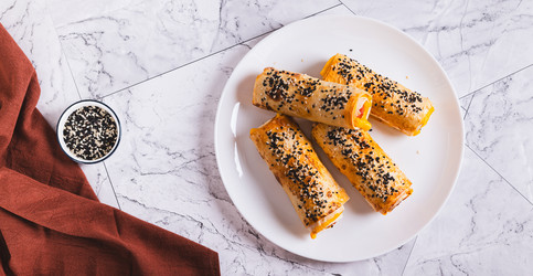 Жареные булочки с сосисками, сыром, питой и кунжутом на тарелке, вид сверху (веб-баннер) - Elena Rui