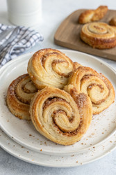 Вкусные пальмиеры из булочек с корицей на белой тарелке. Генеративный ИИ - RomanZ