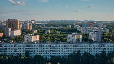 Вид сверху на городской спальный район с типовыми многоэтажными жилыми домами, зелеными зонами и уходящим к горизонту городом - voples