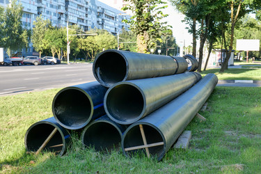 На городском тротуаре лежат большие черные трубы в связи со строительными работами - Gannachka