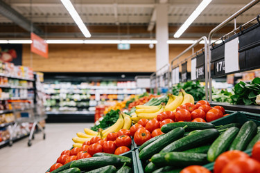 Свежие помидоры, огурцы и бананы выставлены на прилавке продуктового магазина - brillenstimmer