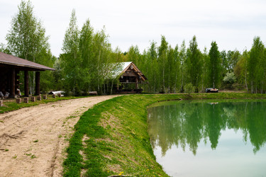 Деревянный дом у озера, где днем деревья отражаются в воде, в окружении природы - VetalanaS