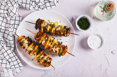 Мясо и картофель, запеченные на шампурах в аэрогриле, лежат на тарелке на столе - Elena Rui