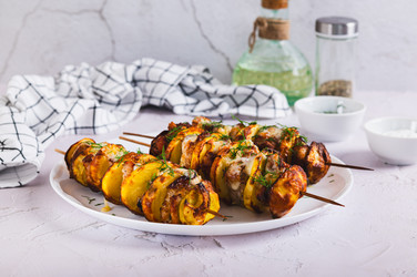 Мясо и картофель, запеченные на шампурах в аэрогриле, лежат на тарелке на столе - Elena Rui