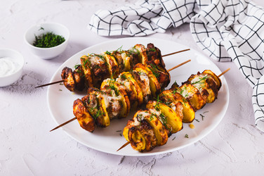 Сульваки — это блюдо из мяса и картофеля, нанизанное на шампуры и подаваемое на тарелке на столе - Elena Rui