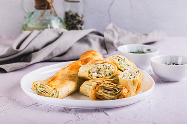 Вкусные поджаренные булочки с творогом, сыром и зеленью на тарелке на столе - Elena Rui
