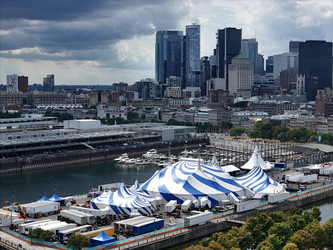24 августа 2025 года. Полет дрона над бело-голубым шатром Cirque du Soleil в Старом порту Монреаля на фоне городского пейзажа - EOS_Canon