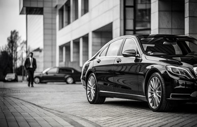Стильный черный автомобиль класса люкс припаркован рядом с современным офисным зданием. Генеративный искусственный интеллект - RomanZ