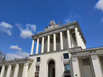 Москва, Россия – 14 мая 2024 года: Недействующий павильон 64 «Оптика» на ВДНХ на фоне ясного неба. Колонны, барельефы, лепнина и скульптурные детали. Общий план. Советская архитектура - Kcuxen
