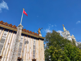 Moscow, Russia – May 14, 2024: Gilded statue of a girl with a wreath in her hand on top of the pavilion 58 against the blue sky at VDNKh. Soviet architecture - Kcuxen