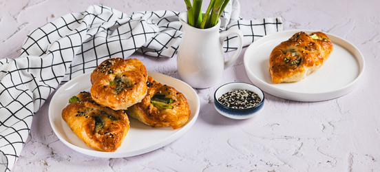 Спаржа, запеченная в слоеном тесте с сыром и кунжутом, на тарелке на столе (веб-баннер) - Elena Rui