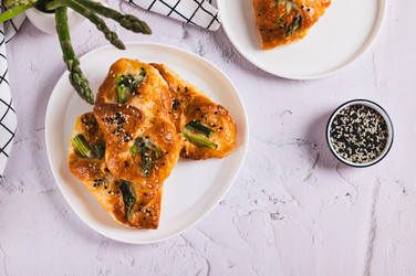 Вкусные слоеные булочки с сыром и спаржей на тарелке, вид со стола - Elena Rui