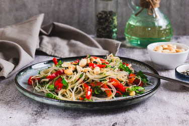 На столе на тарелке стоит вкусный салат из стеклянной лапши, жареного болгарского перца, кинзы и орехов - Elena Rui