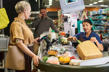 Женщина средних лет с диабетом оплачивает продукты на кассе - Pressmaster