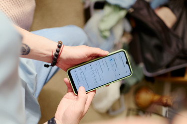 Женщина проверяет бронирование авиабилетов на смартфоне перед отпуском - DragonImagesAsia
