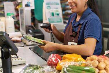 Взрослая латиноамериканка просматривает продукты на кассе супермаркета - Pressmaster
