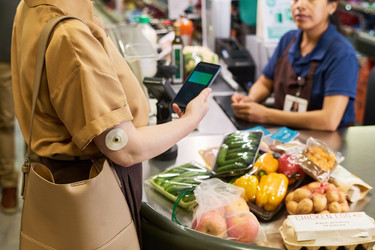Взрослая женщина с диабетом платит за полезные продукты в супермаркете - Pressmaster