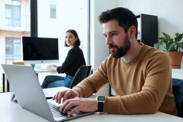 Взрослый мужчина, работающий за ноутбуком в офисе для повышения производительности команды - Mediaphotos
