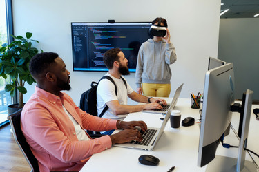 Разнообразные разработчики тестируют виртуальную реальность в software office - AnnaStills