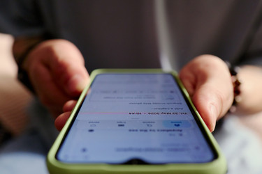 Мужчина держит в руках смартфон, планируя поездку в отпуск онлайн - DragonImagesAsia