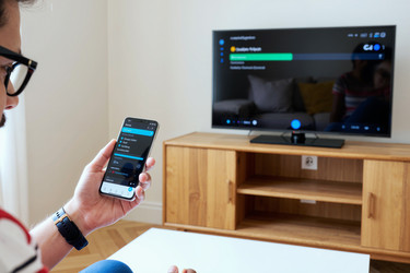 Взрослый мужчина, управляющий smart tv со смартфона дома - DragonImagesAsia