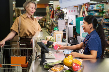 Кассирша-латиноамериканка, помогающая покупателям оформить заказ в продуктовом магазине - Pressmaster