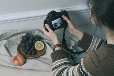 Взрослая женщина фотографирует фрукты для контент-маркетинга продуктов питания - Mediaphotos