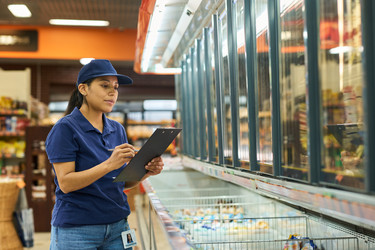 Hispanic Woman Working in Supermarket and Checking Frozen Inventory - Pressmaster
