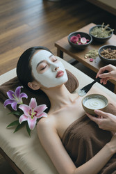 Взрослая азиатская женщина получает маску для лица в спа-салоне wellness - DragonImagesAsia