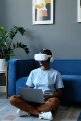 Чернокожая женщина, использующая vr-гарнитуру и ноутбук для удаленной работы - AnnaStills