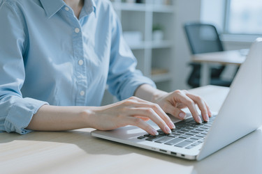 Взрослая женщина печатает на ноутбуке для удаленной работы в офисе - Pressmaster