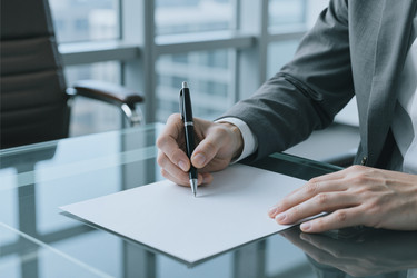 Бизнесмен подписывает документ для корпоративного соглашения в офисе - Pressmaster