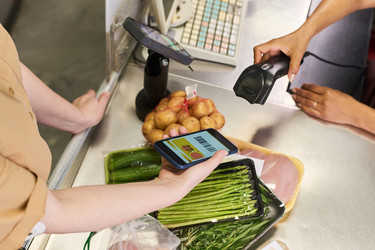 Взрослая женщина с диабетом сканирует продуктовое приложение на кассе супермаркета - Pressmaster
