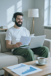 Улыбающийся мужчина в наушниках работает дома за ноутбуком - DragonImagesAsia