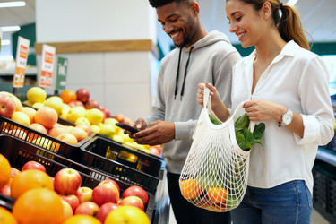 Разнообразная пара, использующая смартфон во время покупок в продуктовом магазине - Pressmaster