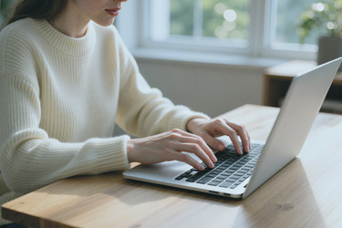 Женщина печатает на клавиатуре ноутбука, работая в домашнем офисе - DragonImagesAsia