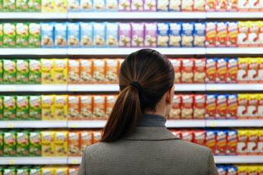 Вид сзади на женщину, выбирающую продукты на полках супермаркета - Pressmaster