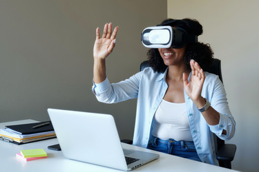 Чернокожая женщина в Vr-гарнитуре во время удаленной работы в домашнем офисе - Pressmaster