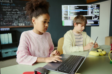 Чернокожая девушка изучает программирование на ноутбуке в классе Stem - DragonImagesAsia