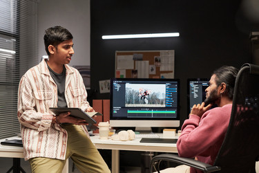 Двое мужчин просматривают видеомонтаж в офисе Creative Production - Pressmaster