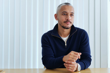 Задумчивый латиноамериканский мужчина, сидящий за письменным столом в современном офисе - DragonImagesAsia