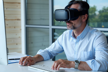Бизнесмен средних лет в Vr-гарнитуре работает за офисным столом - Pressmaster