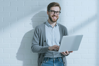 Портрет улыбающегося мужчины с ноутбуком в руках для удаленной работы - DragonImagesAsia