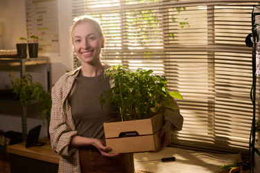 Портрет позитивной женщины, держащей в руках саженцы для городского фермерского бизнеса - Pressmaster