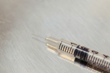 Медицинский шприц, лежащий на поверхности для вакцинации и оказания медицинской помощи - DragonImagesAsia