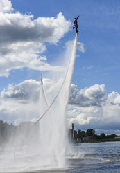 Двое спортсменов выполняют трюки на флайбордах над водной гладью озера Сенеж - Sadoff
