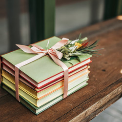 Разноцветная стопка книг, перевязанных лентой, на деревянном столе. Генеративный ИИ - RomanZ